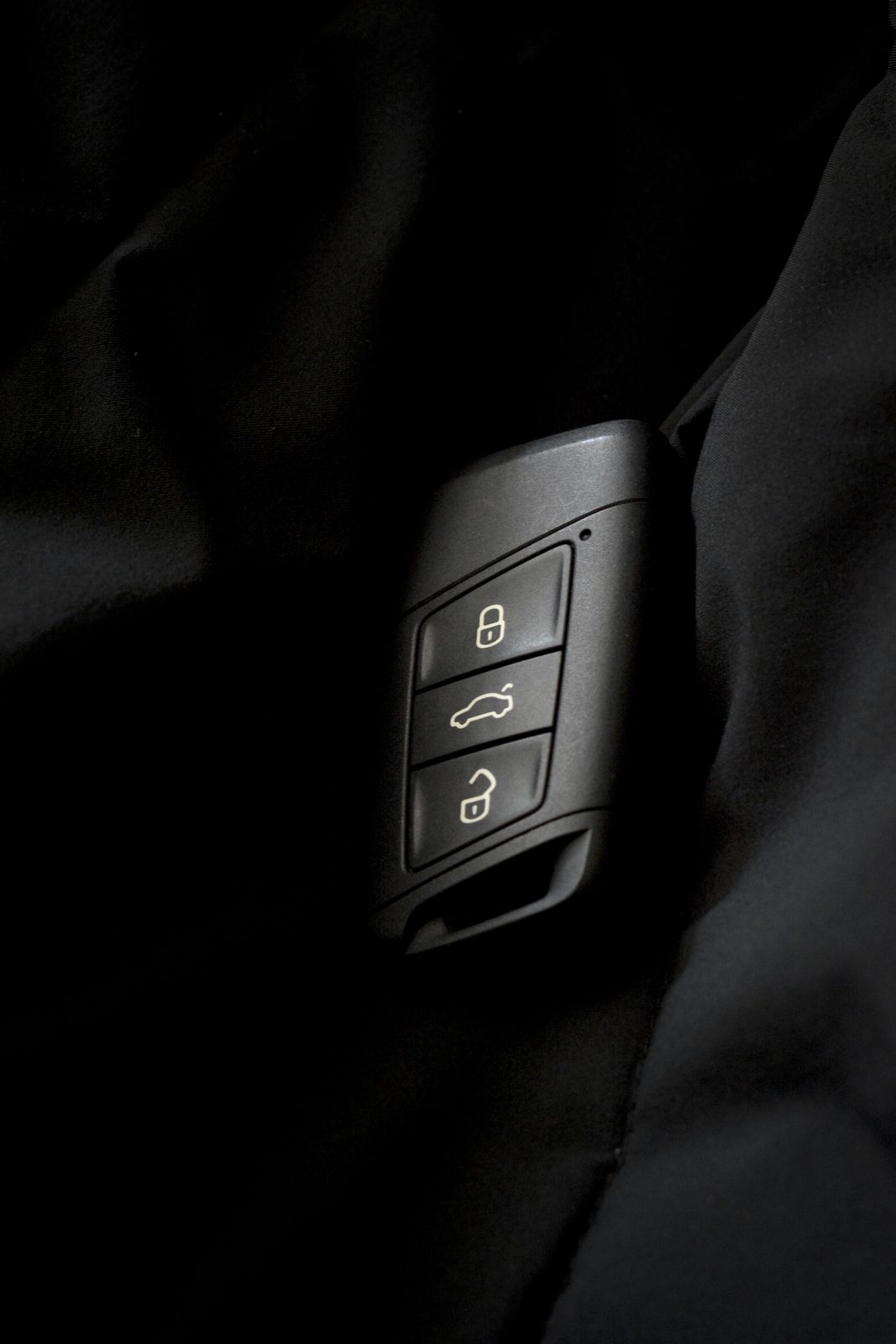 A modern car key fob showing lock, trunk, and unlock buttons