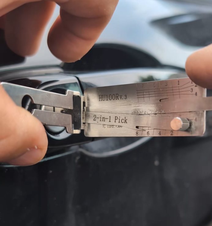 A locksmith's Lishi HU100R 2-in-1 pick on a car door during a lockout