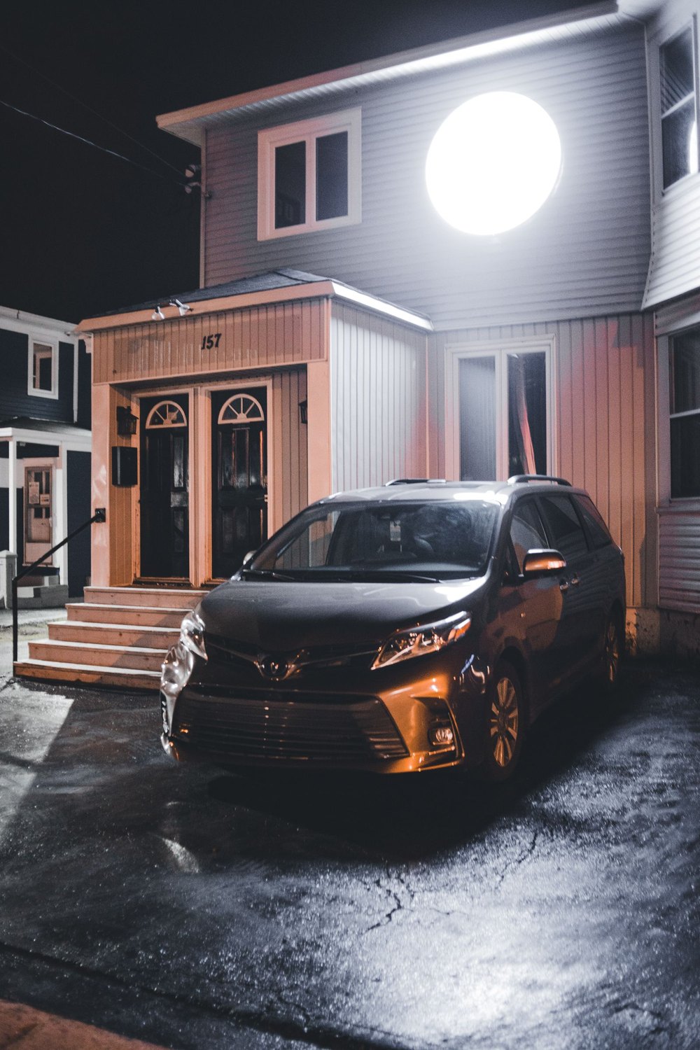 A locksmith's minivan parked in the driveway at night outside a warmly lit home